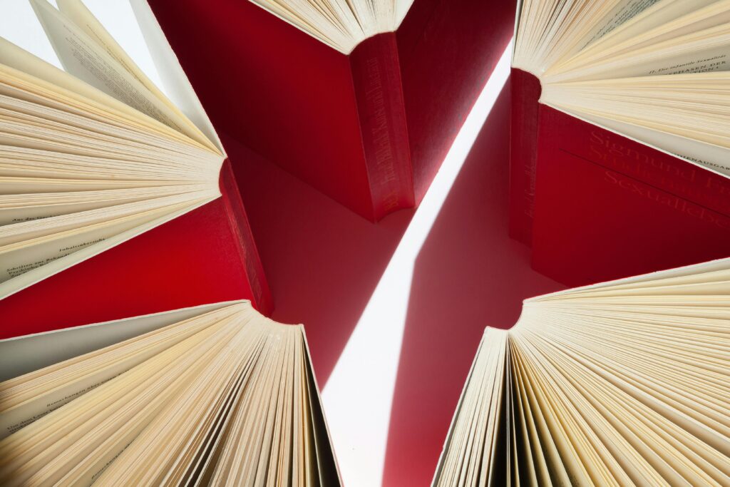 An artistic display of open books with red covers arranged in a star-like pattern.